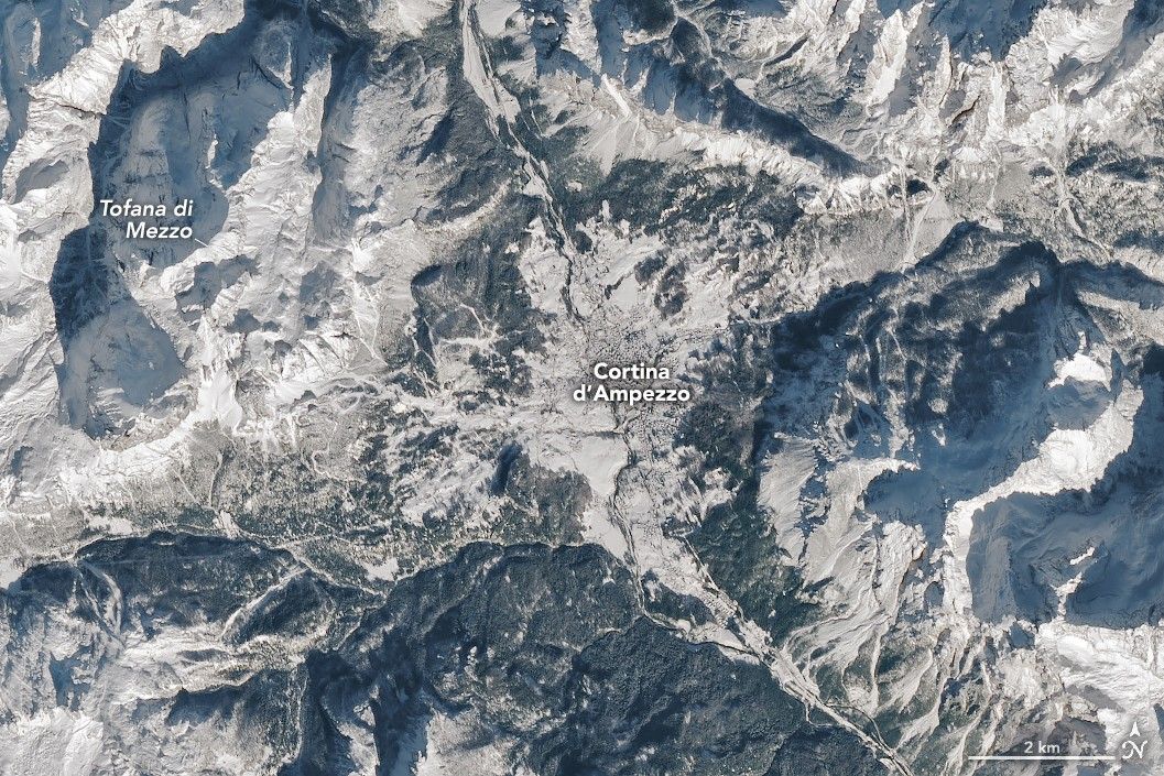 Cortina d’Ampezzo, Italy, co-host city of the 2026 Winter Olympics, sits in a valley surrounded by tall mountains in the Dolomites. Snow covers the ground in most of the scene.